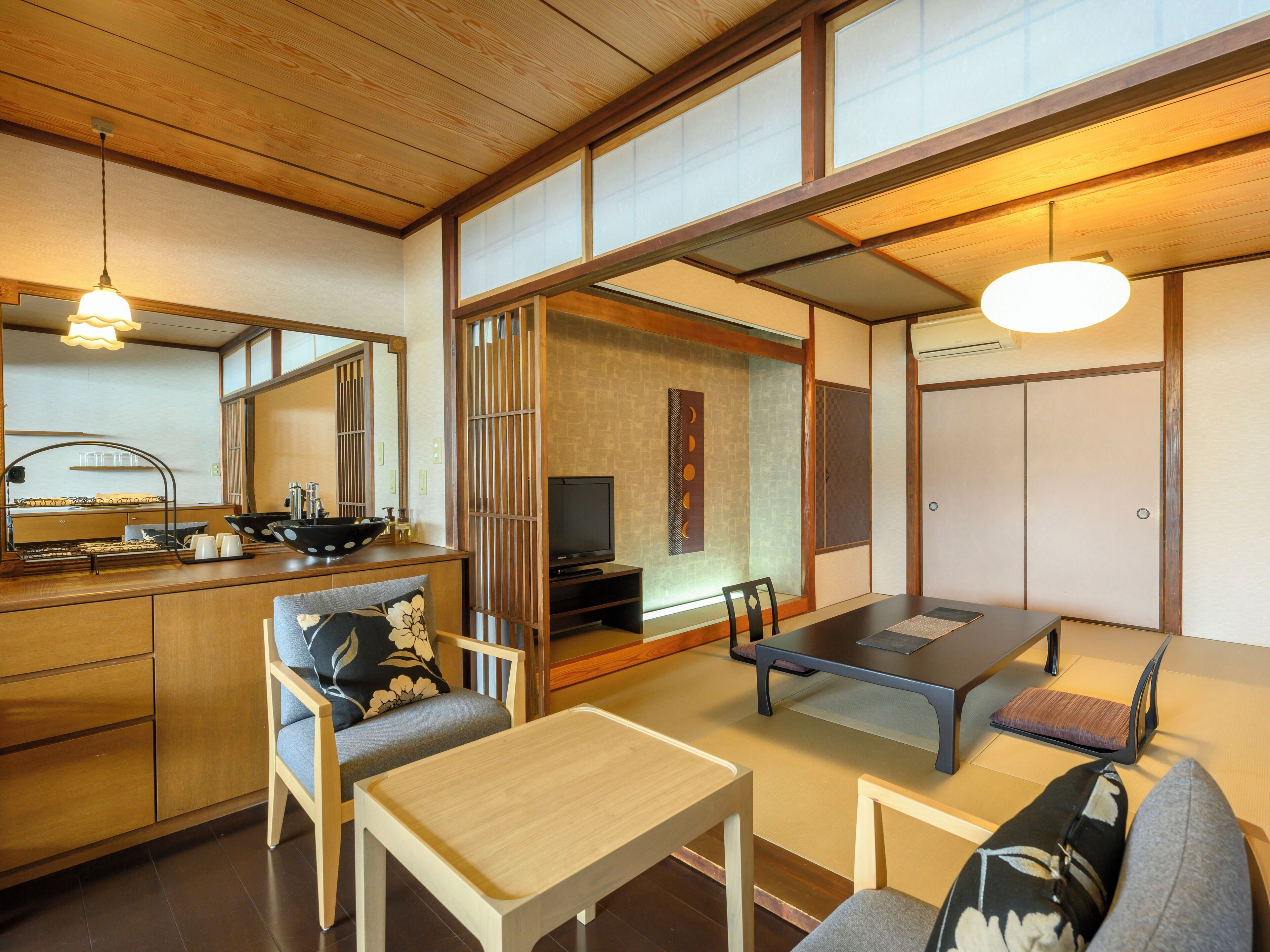 Une pièce de style japonais traditionnel, avec un sol recouvert de tatamis, une table basse, un canapé et un téléviseur.