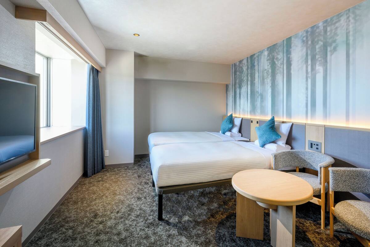 Ein Hotelzimmer mit Bett, Fernseher, kleinem Tisch und Stuhl.