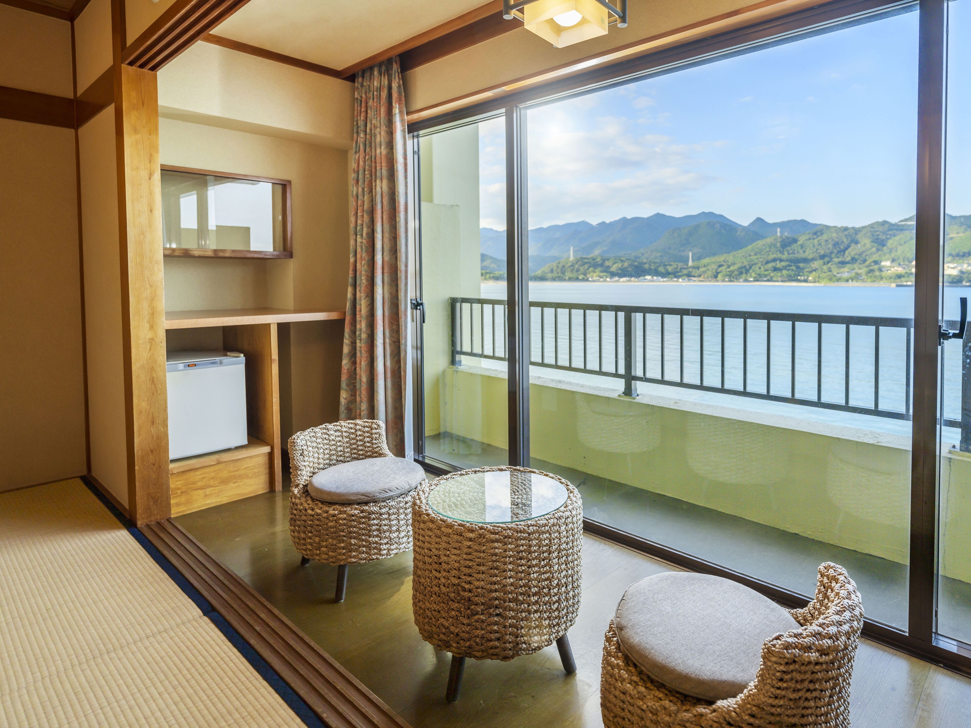 A balcony with wicker furniture and a view of mountains.