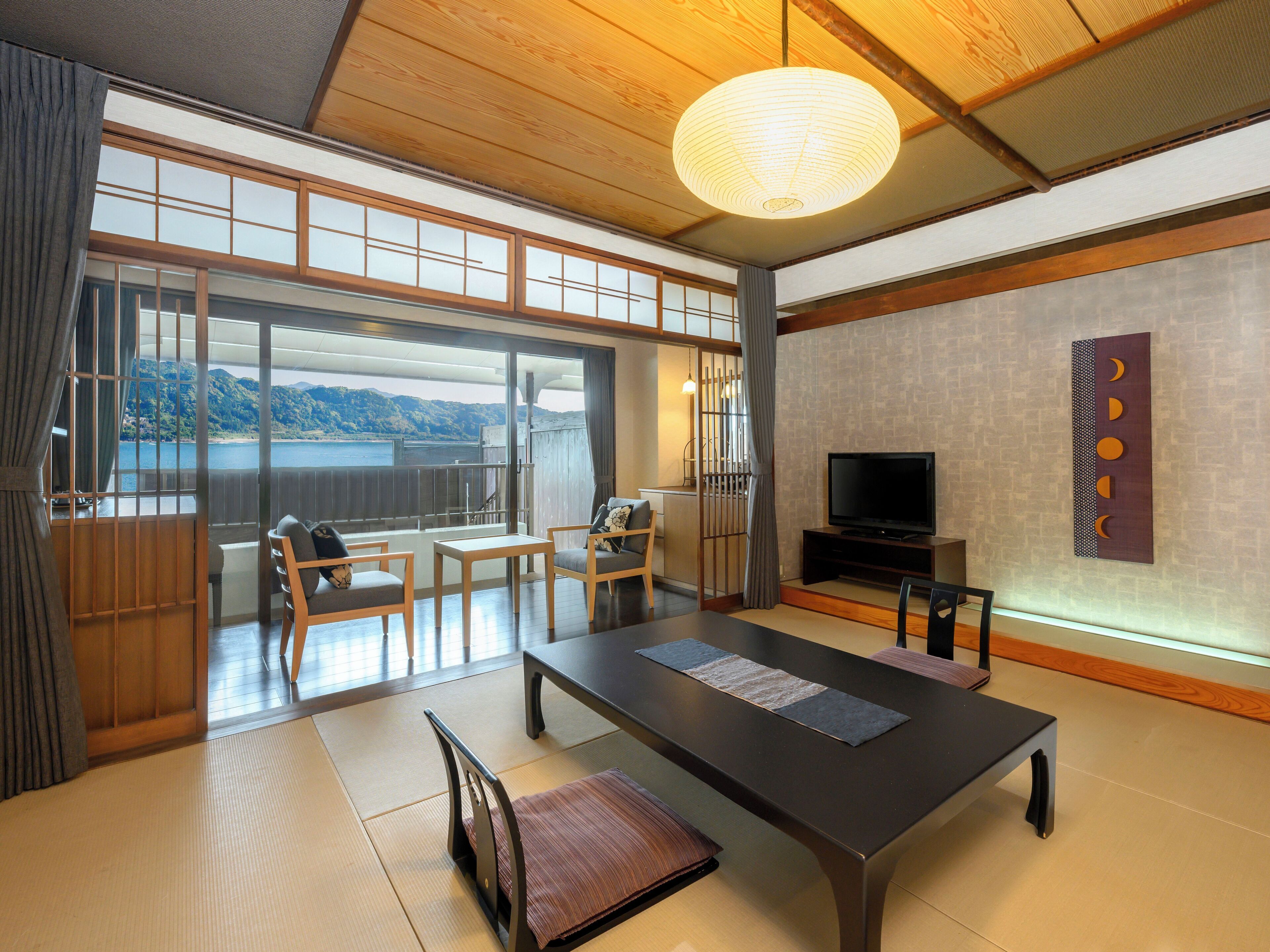 A traditional Japanese-style room with tatami flooring, a low table, and a television.
