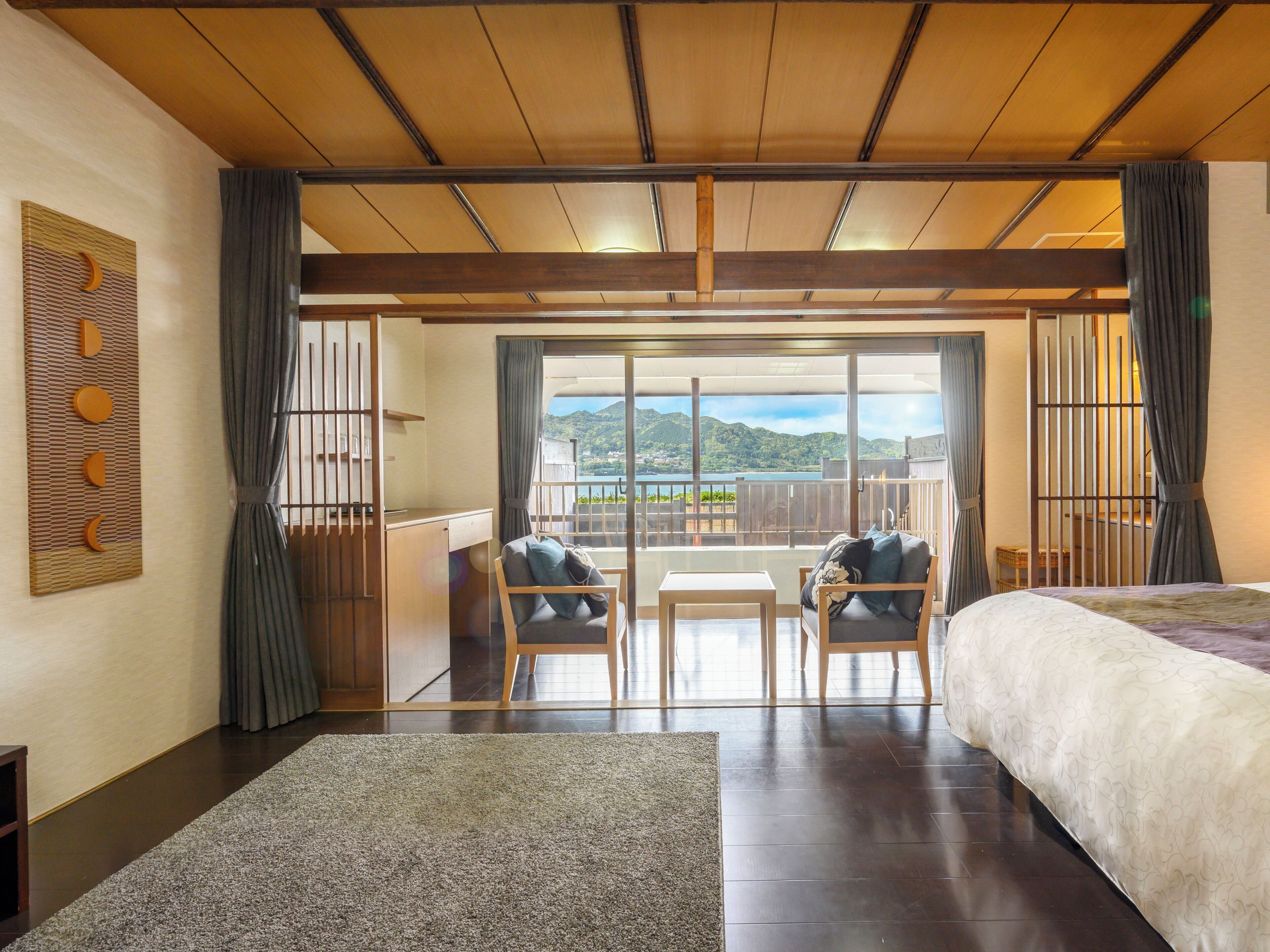 A hotel room with a balcony, wooden ceiling, and a view of the mountains.