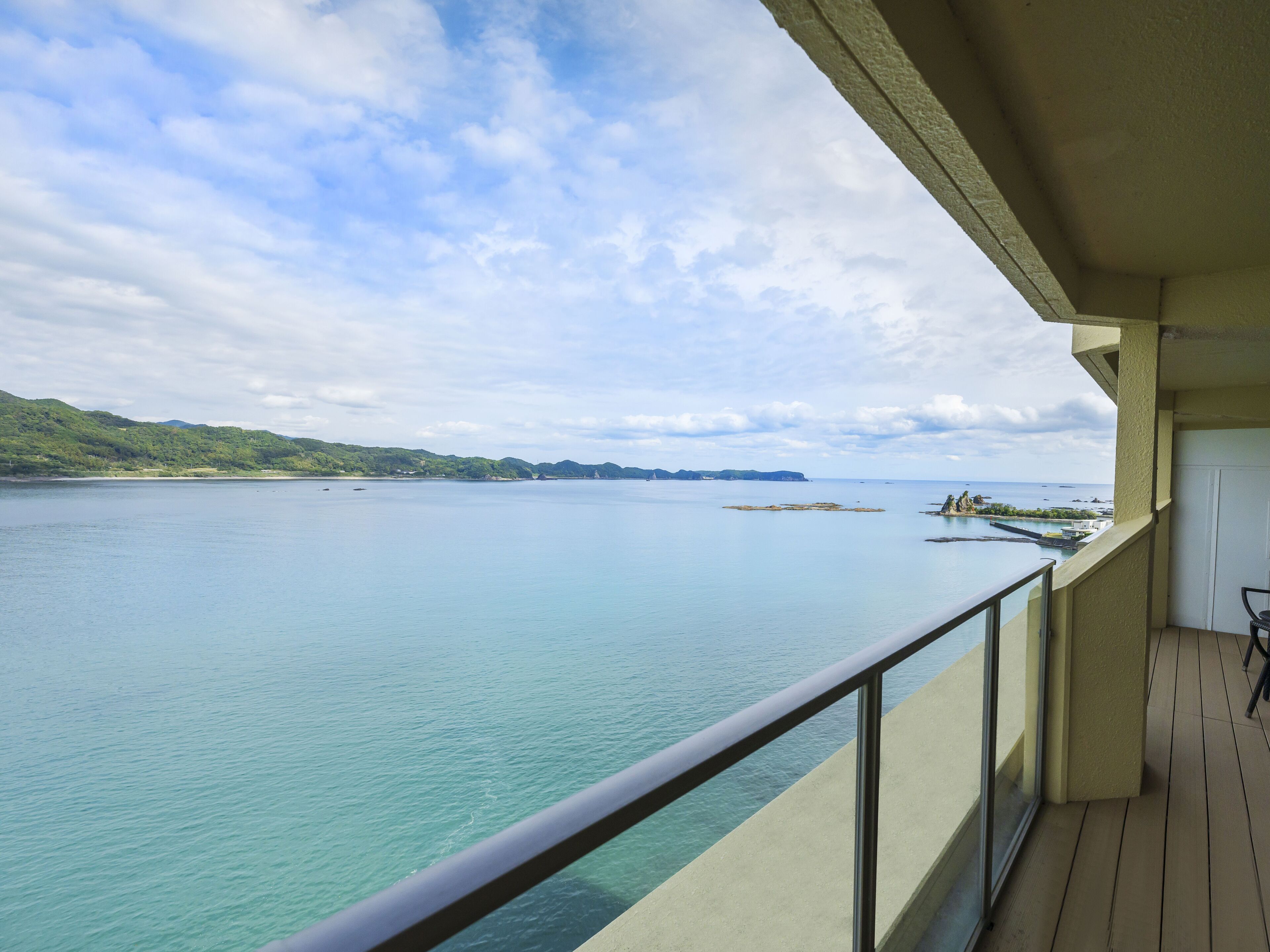 Balkon med udsigt over roligt hav og land i det fjerne.