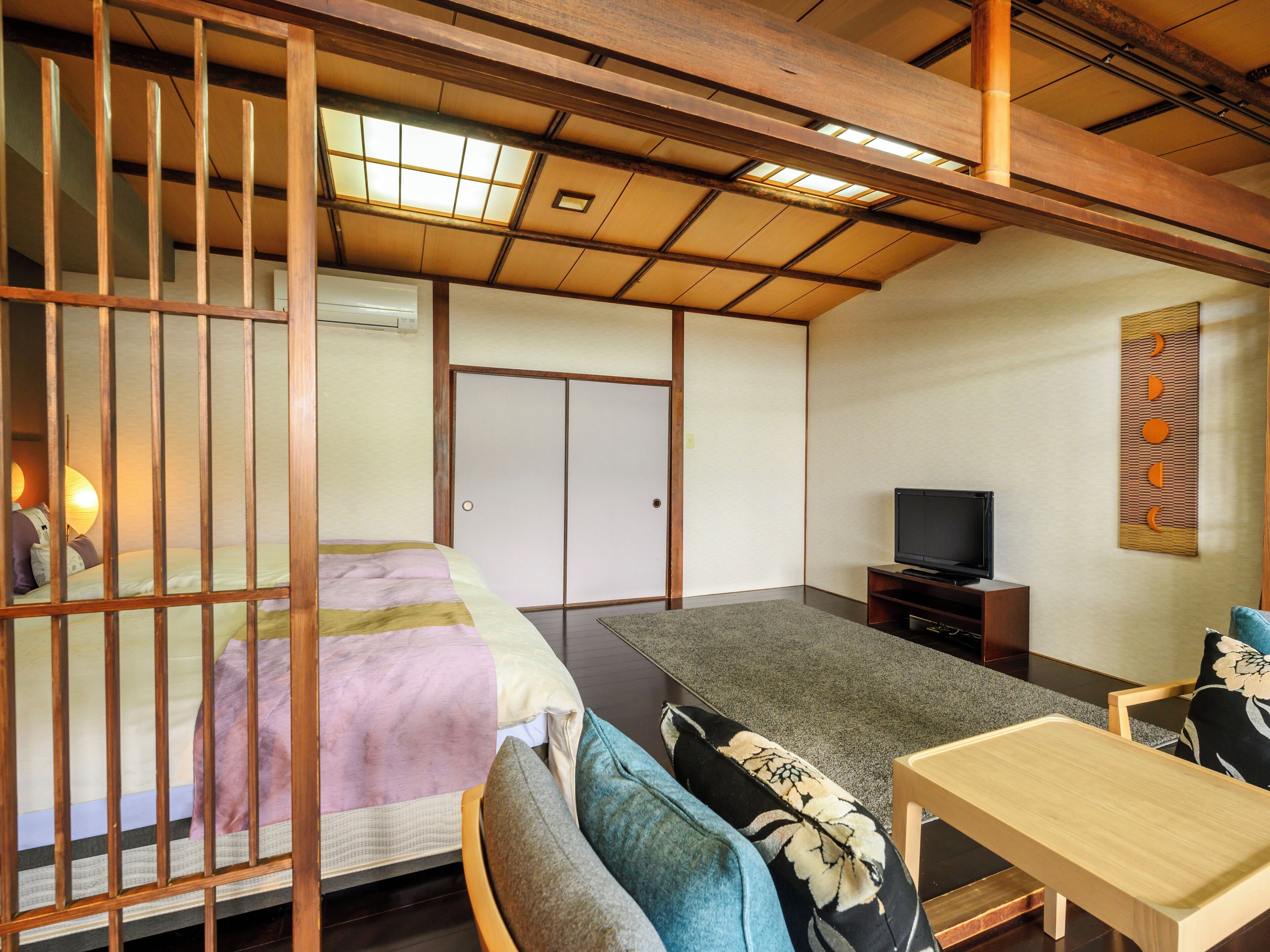 A traditional Japanese room with tatami flooring, a low wooden bed, a television, and a sliding door.