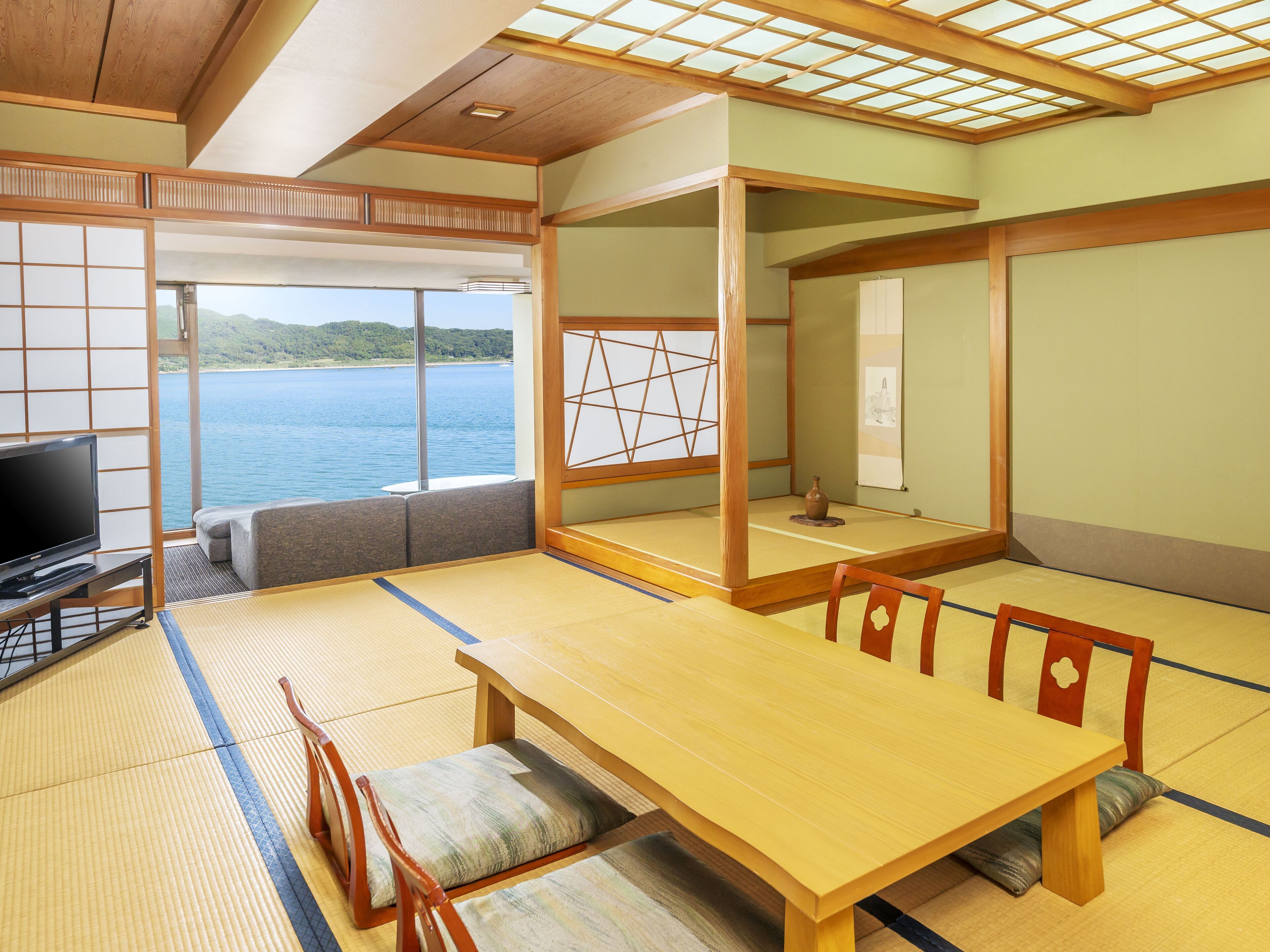 Um quarto japonês tradicional com tatames, uma mesa baixa e uma televisão.