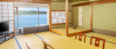 Um quarto japonês tradicional com tatames, uma mesa baixa e uma televisão.