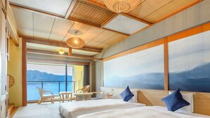 A hotel room with two beds, a small table, chairs, and a view of the sea.