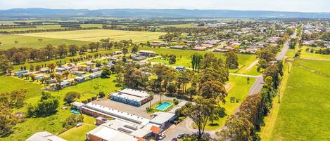 An aerial view of a residential area with houses, a swimming pool, and a large industrial building.