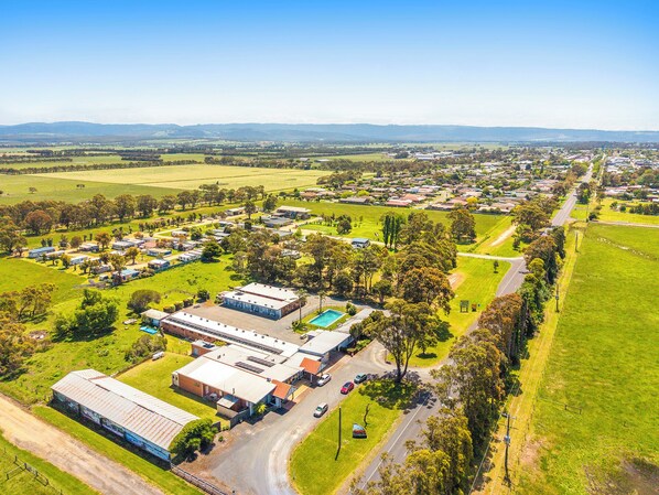 An aerial view of a residential area with houses, a swimming pool, and a large industrial building. - Ship Motel Yarram (Yarram)