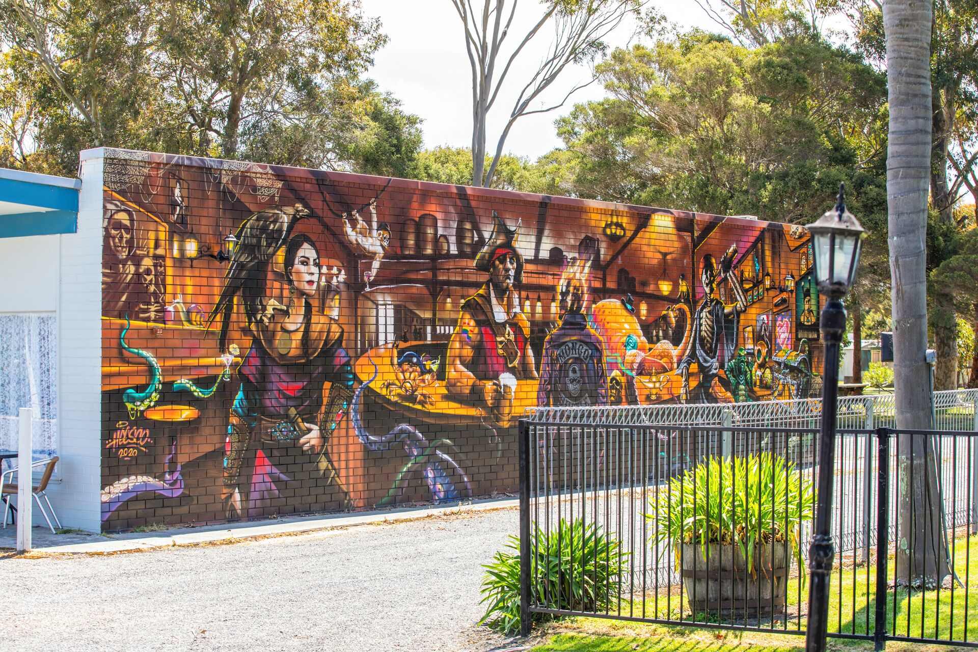 A mural on a brick wall with a metal fence in front.