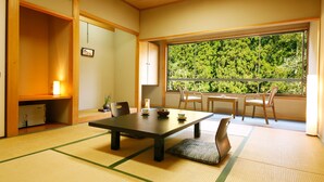 A traditional Japanese room with tatami flooring, a low table with a cushion, and a view of a forest through a large window. - Kyoto Miyama Ryori Ryokan Chinsenro (Nantan)