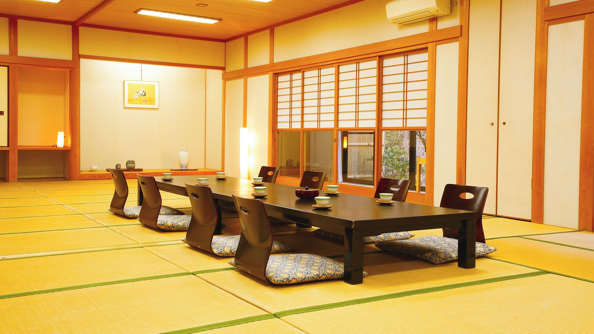 Een traditionele Japanse kamer met tatami vloerbedekking, een lage tafel met kussens en verschuifbare shoji deuren.