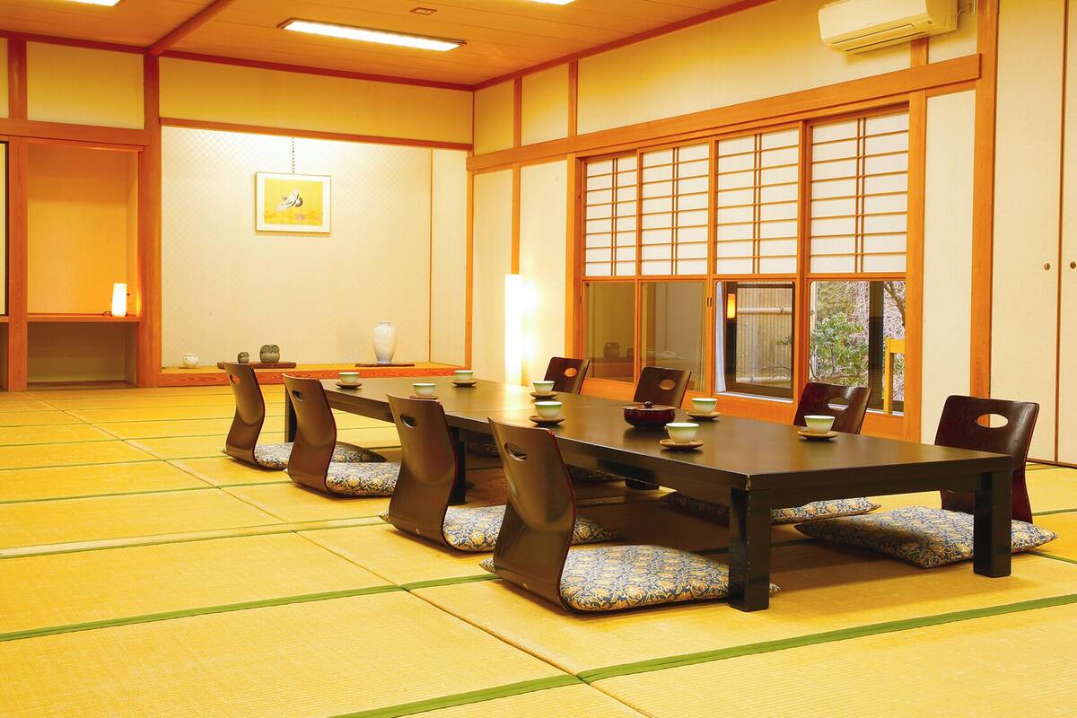 A traditional Japanese-style room with tatami flooring, a low table with cushions, and sliding shoji doors.