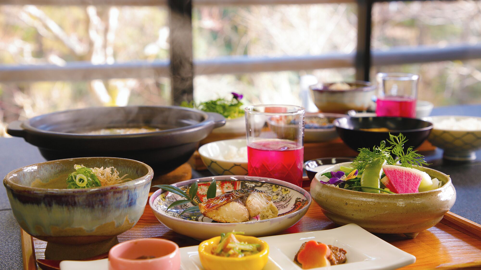 A variety of traditional Japanese dishes and drinks on a wooden table.