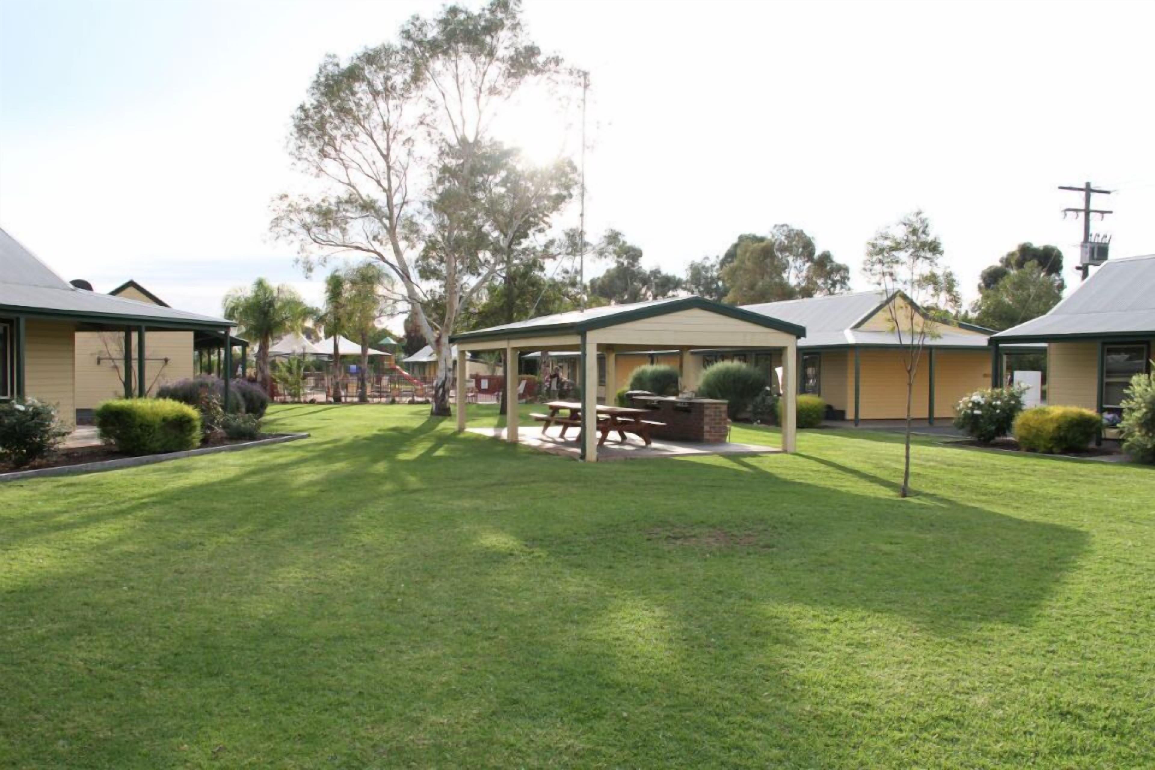 A courtyard with a covered seating area, a picnic table, and a small play area.