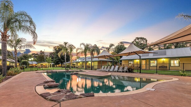 Ein Resort mit Pool, Liegestühlen und Blick auf den Sonnenuntergang.