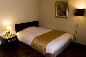 A hotel room with a bed, a nightstand with a lamp, and a painting on the wall. - Hotel Urban Ikebukuro (Tokyo)