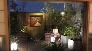 A courtyard with a wooden fence, potted plants, and a tiled floor.