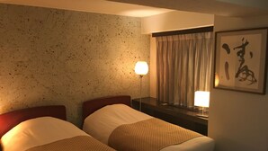 A hotel room with two beds, a nightstand, a lamp, a window with curtains, and a wall with a framed picture.