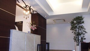 A reception area with a marble counter, a potted plant, and a modern ceiling design.