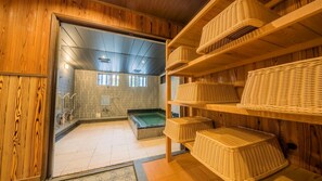 A traditional wooden interior with a hot spring bath, shelves with woven baskets, and a tiled floor. - Ekoin (Koya)