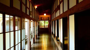 A corridor with wooden beams and tatami mat flooring, leading to a traditional Japanese entrance. - Ekoin (Koya)