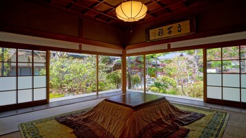 Una habitación tradicional japonesa con suelo de tatami, una mesa baja y un farol de papel colgante.