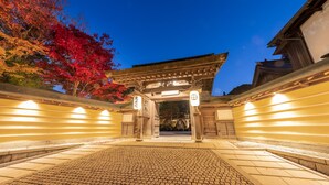 A traditional Japanese torii gate with a paved walkway leading to it, surrounded by autumn foliage. - Ekoin (Koya)