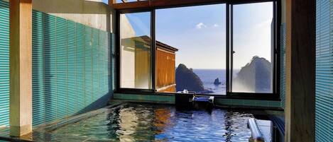 A traditional Japanese onsen with a view of the sea through large windows.