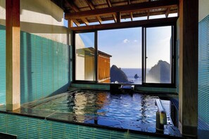 Un onsen japonès tradicional amb vista al mar a través de grans finestres.