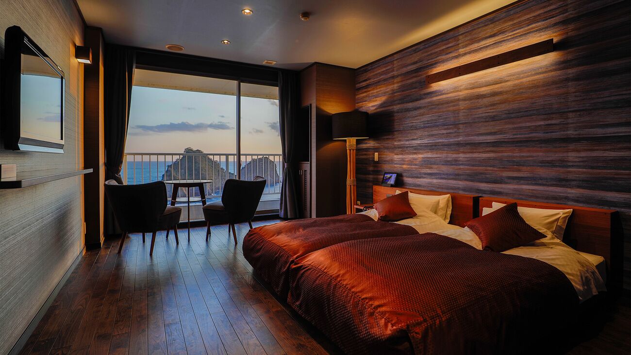 Een moderne hotelkamer met een groot bed, een balkon met uitzicht en een houten wand.