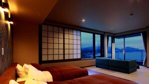 A modern hotel room with two beds, a large window with a view of mountains, and a traditional Japanese shoji screen. - Dogashima Hotel Tenyu (Nishiizu)