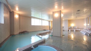 A large indoor swimming pool with a separate hot tub area, tiled walls, and a seating area with towels. - Towadako Lakeview Hotel (Kosaka)