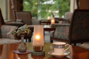 A table with a candle, a cup, and a vase with a plant. - Towadako Lakeview Hotel (Kosaka)