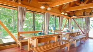 A wooden cabin with large windows, wooden benches, and a dining table. - Towadako Lakeview Hotel (Kosaka)