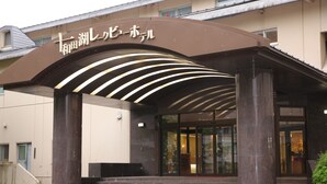 A hotel entrance with a curved awning and steps leading up to the door. - Towadako Lakeview Hotel (Kosaka)