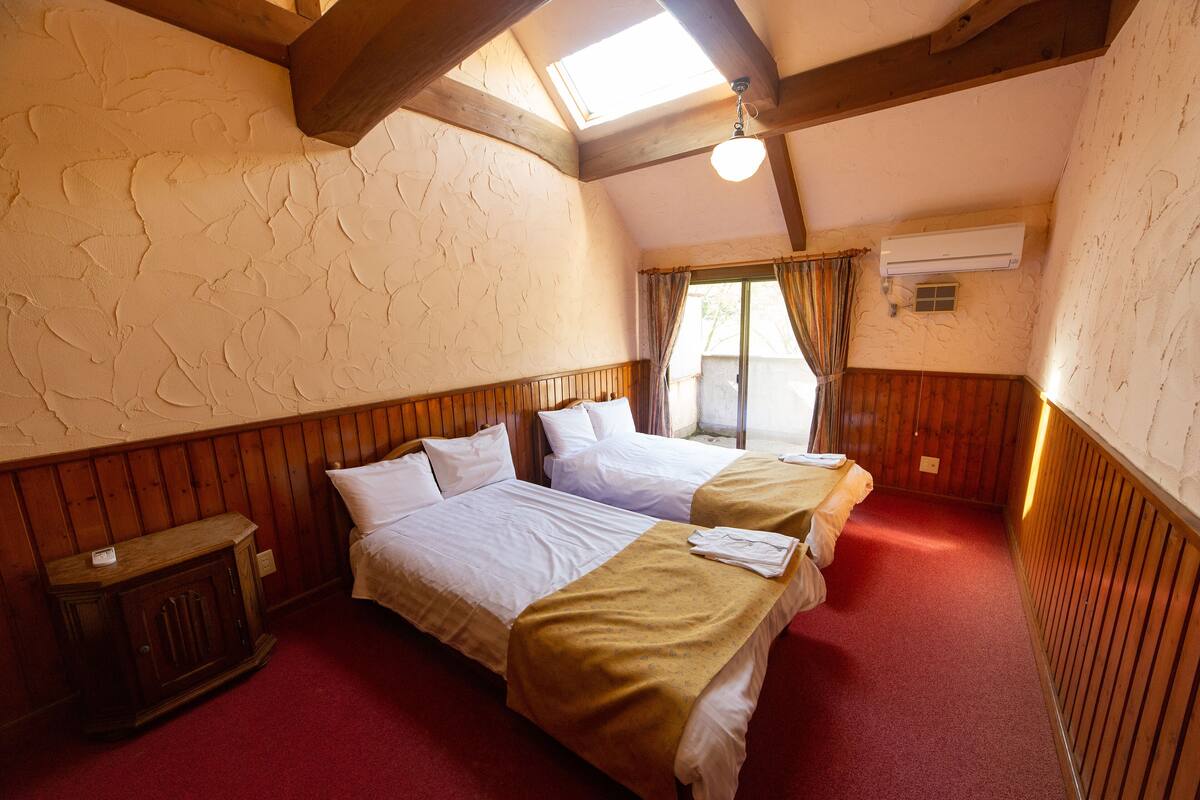 Un dormitorio con dos camas, paneles de madera, tragaluces y un equipo de aire acondicionado.