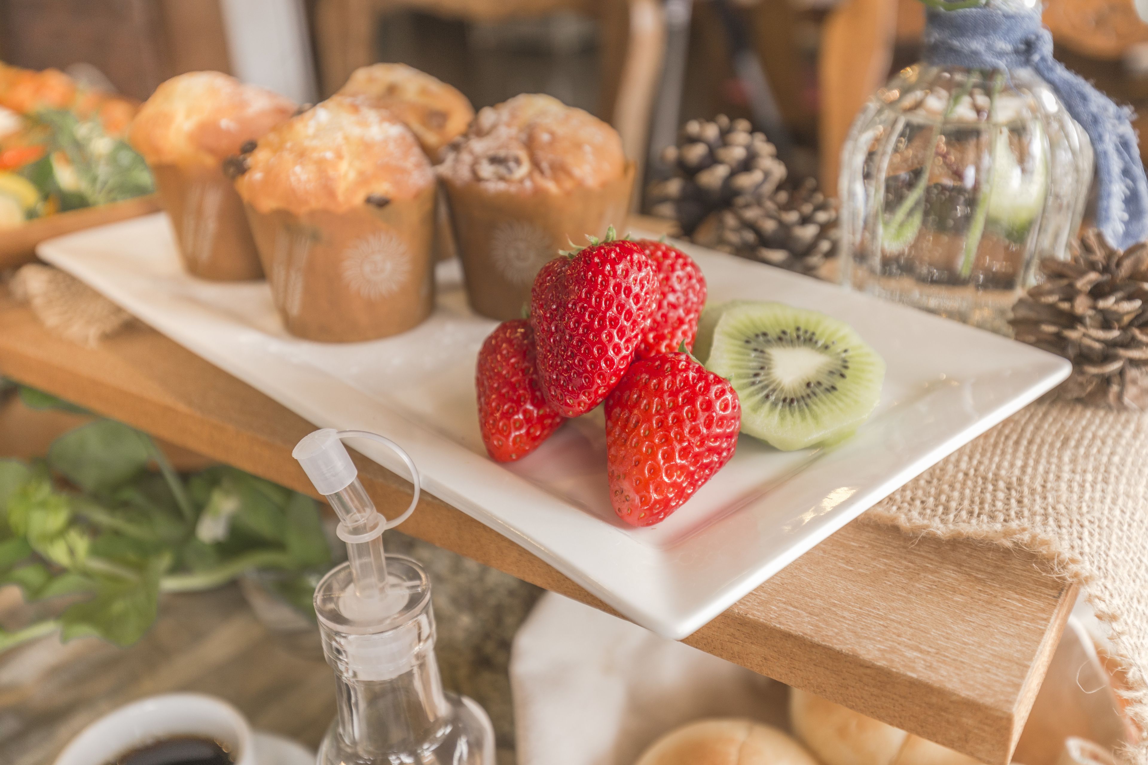 Un plateau contenant des pâtisseries, des fraises et des kiwis, posé sur une table en bois.