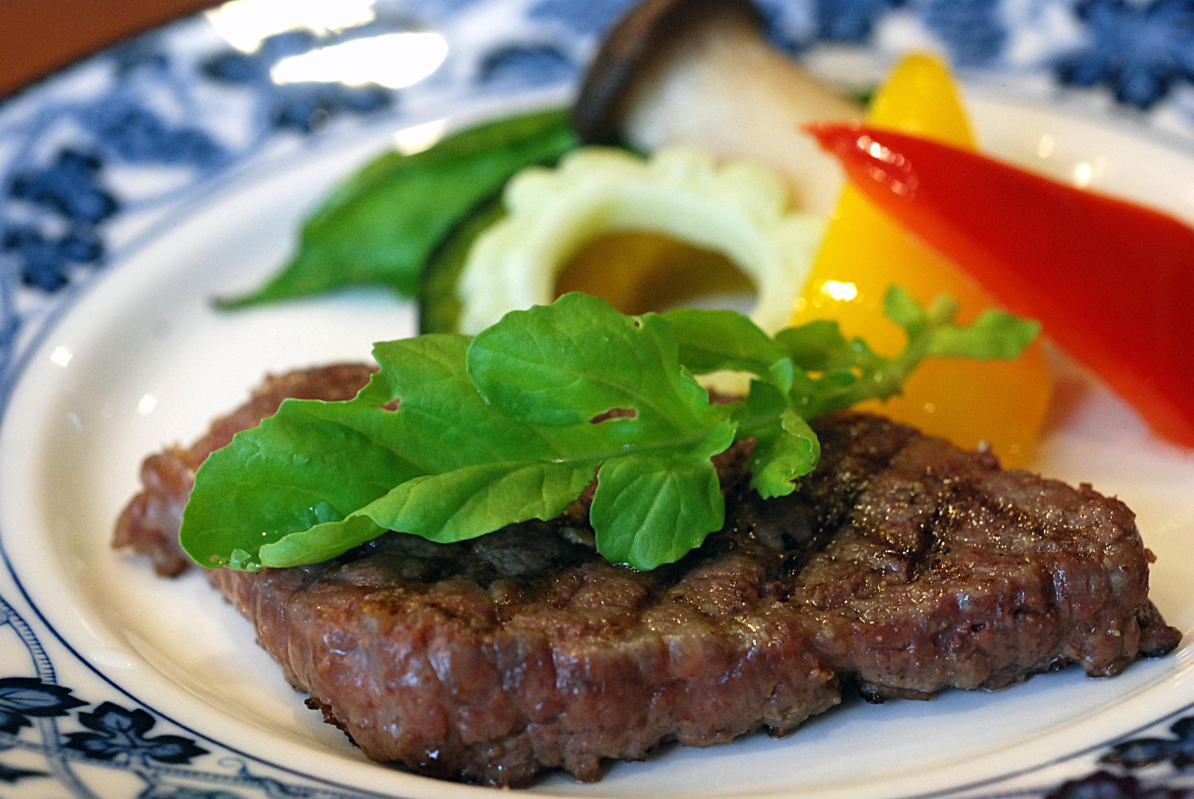 A plate with a steak, avocado, and vegetables.
