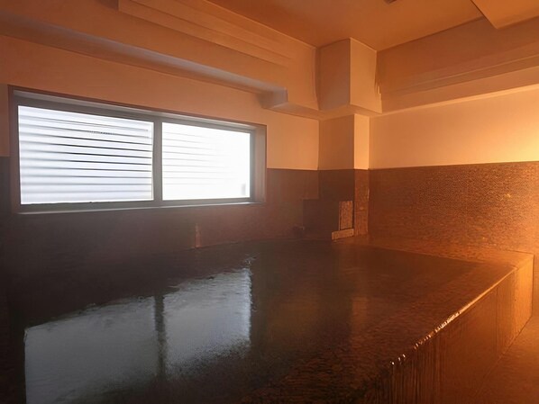 A room with a large window, a dark polished floor, and a partial view of a wall with a textured finish.