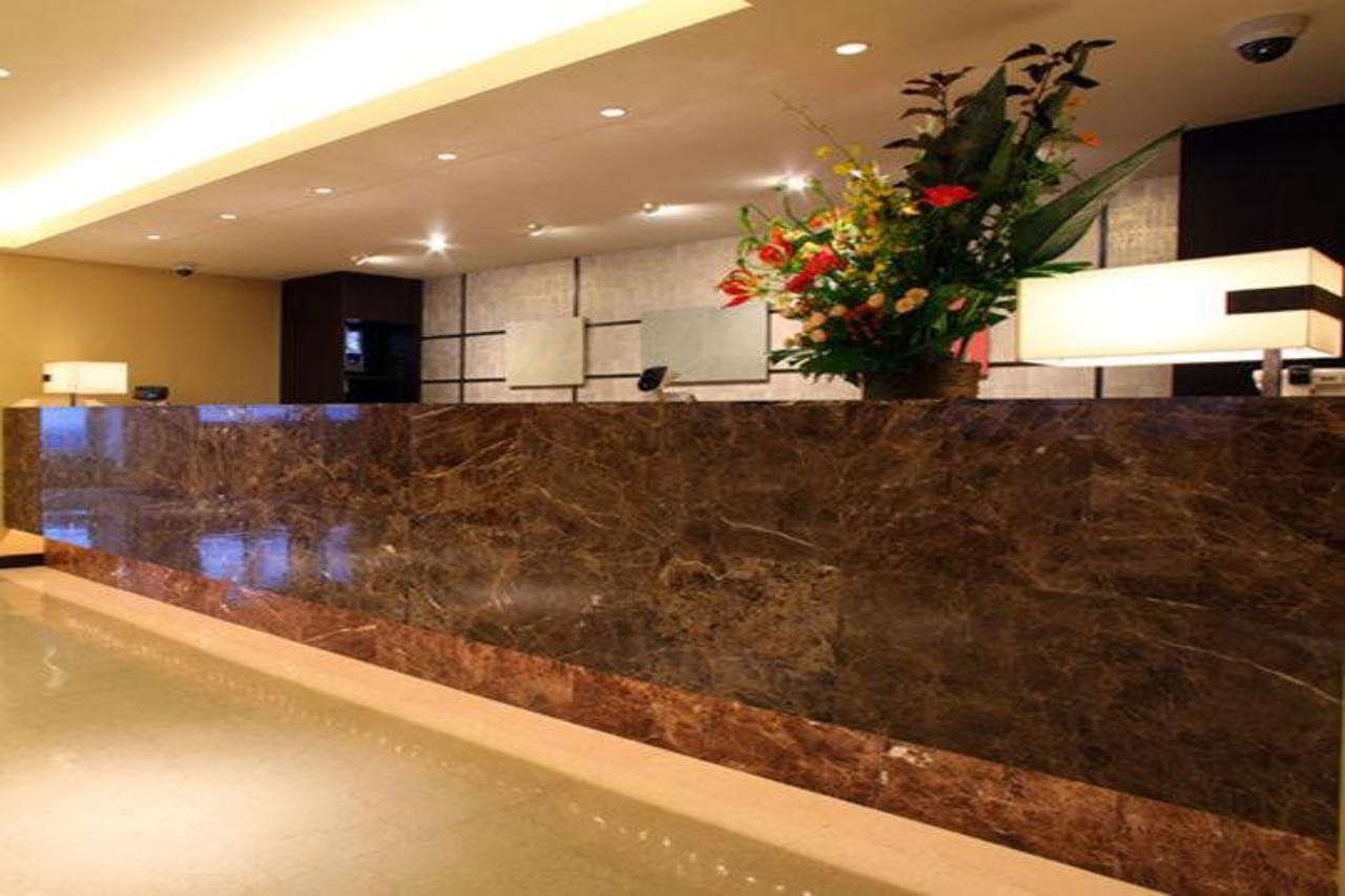 A reception area with a marble counter, a potted plant, and a reception desk.