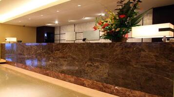 A reception area with a marble counter, a potted plant, and a reception desk.