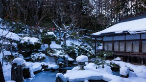 A traditional Japanese building with a snow-covered garden, including a pond and rocks. - Ichijoin (Koya)