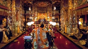 An ornate temple interior with a central statue, intricate decorations, and a red floor. - Ichijoin (Koya)