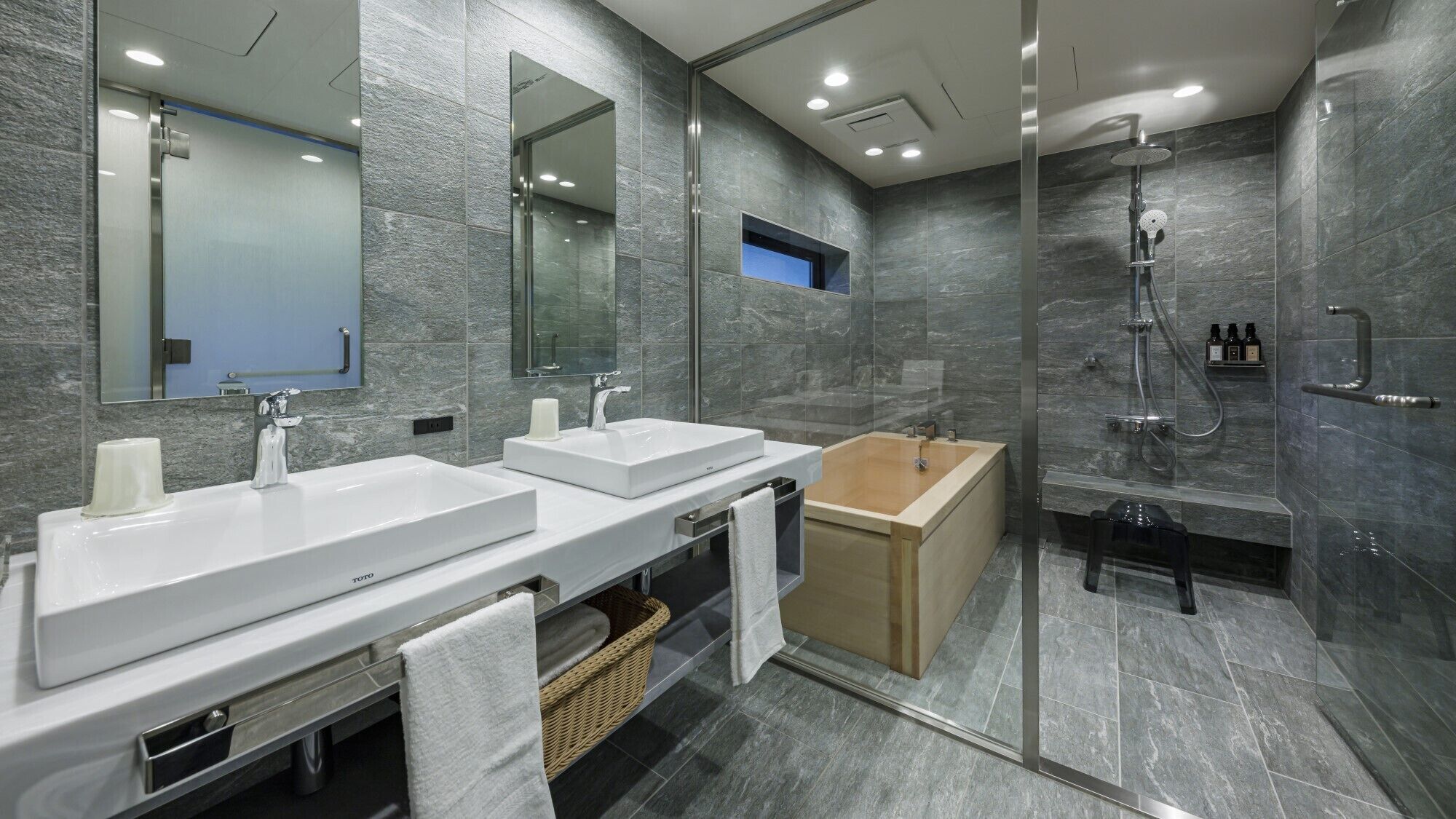 A modern bathroom with two sinks, a bathtub, and a glass-enclosed shower area.