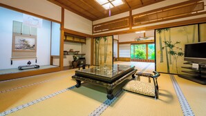 A tatami mat room with a low table, a cushion, a television, and traditional Japanese decor. - Ichijoin (Koya)