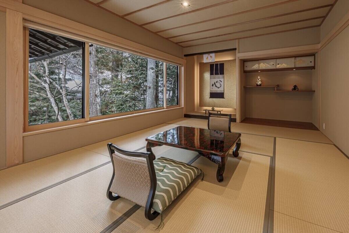 A tatami mat room with a low table, cushions, and a shelf with decorative items.