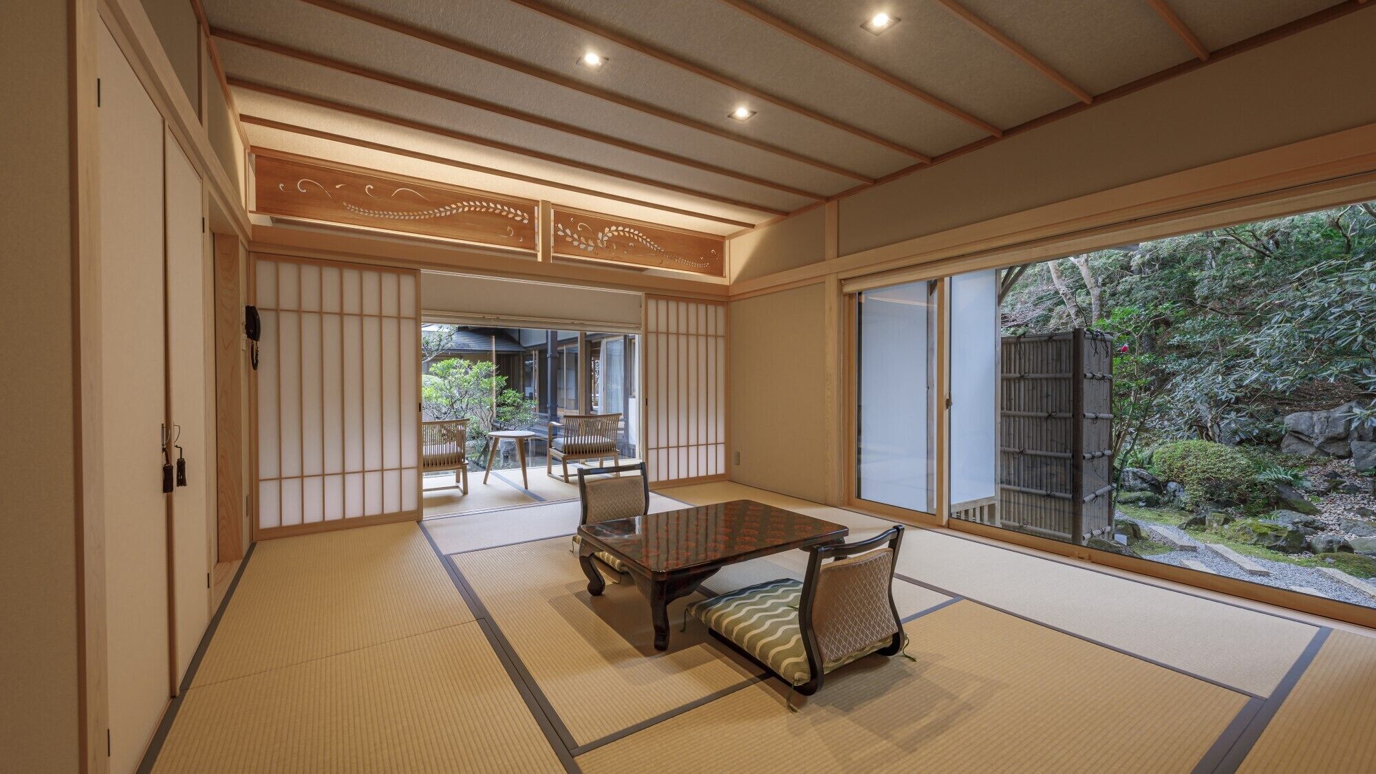A traditional Japanese room with tatami flooring, a sliding door, and a view of a garden.
