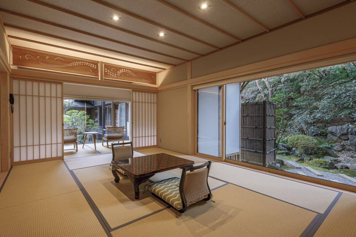 A traditional Japanese room with tatami flooring, a sliding door, and a view of a garden.