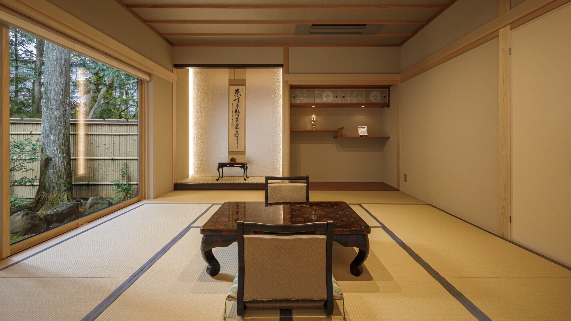 A traditional Japanese room with tatami flooring, a low table, a chair, and a sliding door leading to a garden.