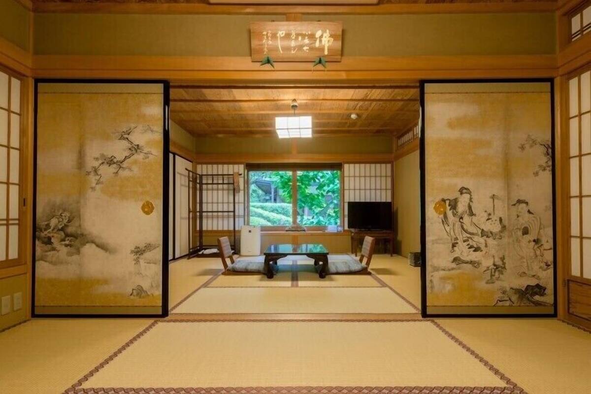 A traditional Japanese room with tatami flooring, a television, and artwork on the walls.